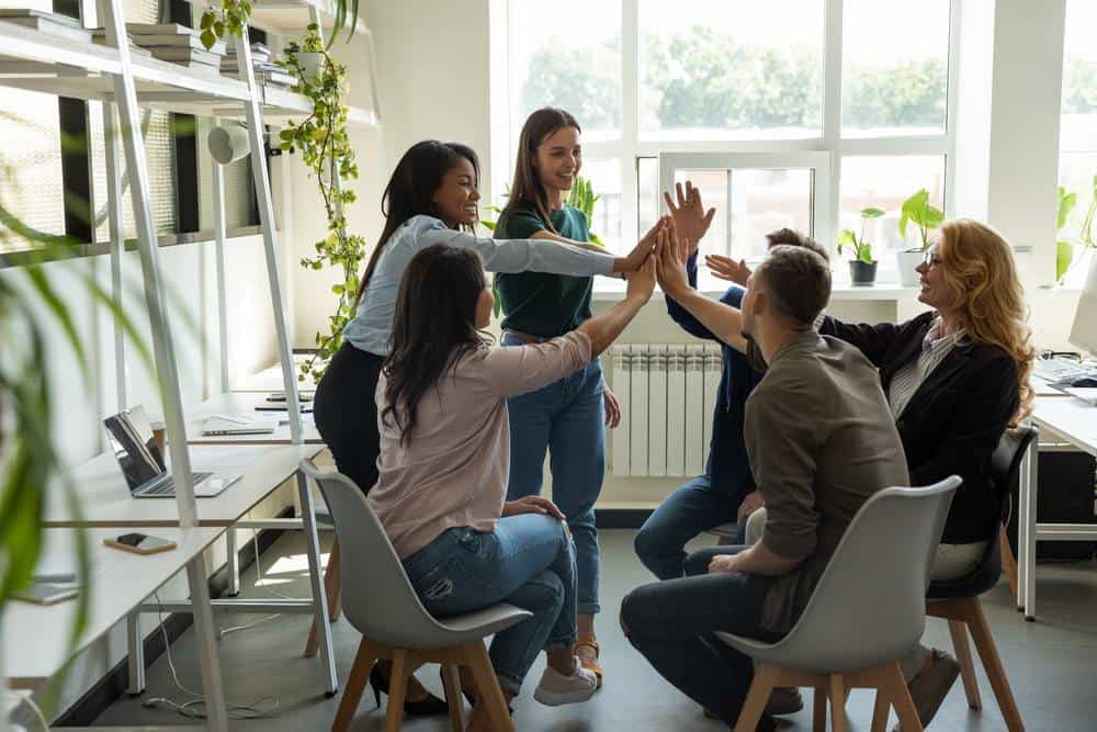 Team of office workers hi-fiving to celebrate small achievments